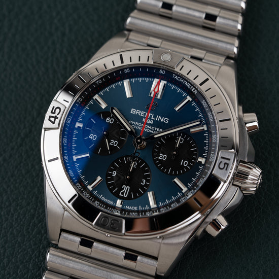 Breitling Chronomat AB0134101C1A1 - close-up frontaal onder een hoek met blauwe wijzerplaat en stalen Rouleaux band