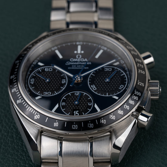 Omega Speedmaster Racing 326.30.40.50.03.001 - close-up van de wijzerplaat met tachymeterbezel, kroon en drukkers rechts