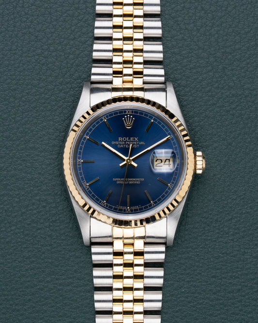 Rolex Datejust 16233 Blue Dial - frontaal aanzicht met blauwe sunburst wijzerplaat, gouden fluted bezel en Jubilee band